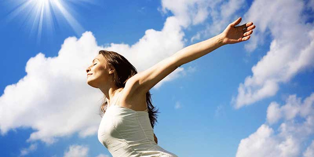 woman in white dress with arms outstretched on sunny day